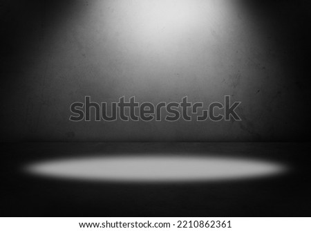 Empty gray floor and blank dark grey concrete wall in spotlit light interior garage studio room. Copy space or product display.