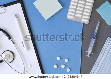 Empty gray modern doctor desk table with mask, notepad, syringe. Copy space, flat lay. Top view. Medicine and healthcare, cardiology, medical education. Blank space for text. Paper sheet for text