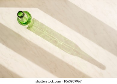 Empty green bottle on the marble surface under the natural light of the sun