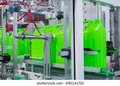 Empty green plastic jerrycans moving on conveyor belt of automatic pet blow molding machine at factory, exhibition. Manufacturing, recycling, industry, automated technology equipment concept