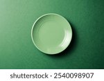 Empty green plate on green background. Top view. Copy space.