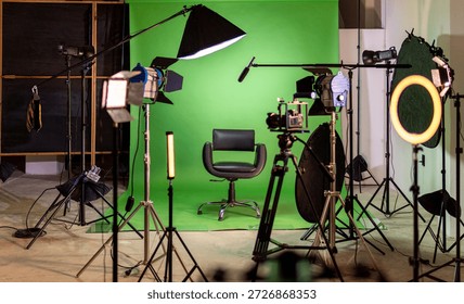 Empty green screen studio with camera, lighting, and an interview chair ready for production
