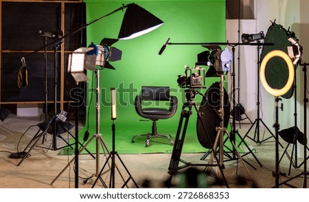 Empty green screen studio with camera, lighting, and an interview chair ready for production