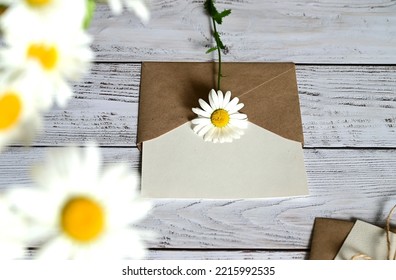 An empty greeting card with a brown envelope and a white flower for mom on a wooden table in vintage style and with vignettes - Powered by Shutterstock