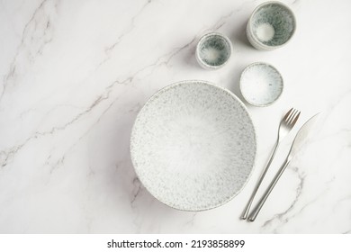 Empty Grey Ceramic Scandy Soup Bowl, Espresso Coffee Mugs And Dip Bowl, Fork And Knife On A Marble Surface And Kitchen Towel, Top View