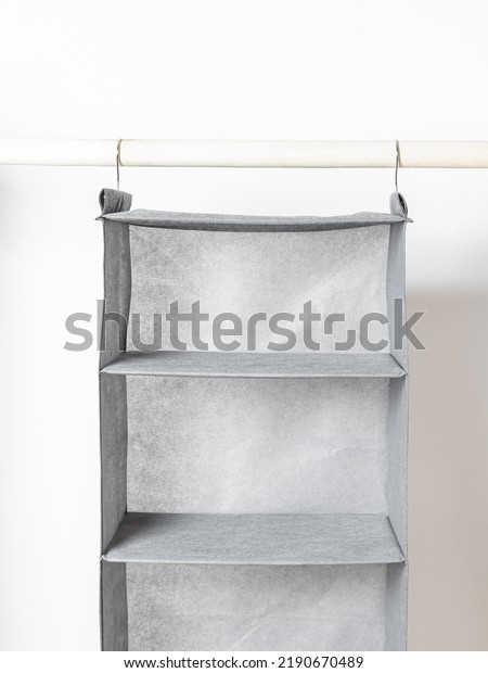 Empty grey hanging\
organizer for clothes. Storage system for wardrobe.Storage\
compartments 