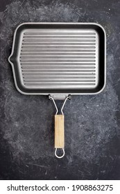 
Empty Grill  Pan On Black Grunge Background, Top View. Clean Cast Iron Griddle, Overhead View. Square Empty Grill Pan On Black Shabby Table.