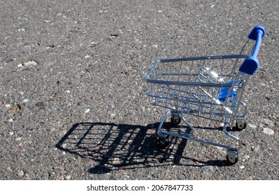 Empty Grocery Cart In An Empty Parking Lot Near A Supermarket.