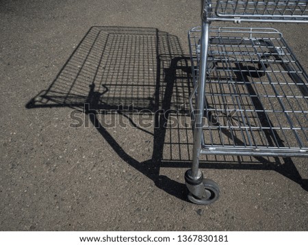 Empty grocery cart. The shadow of the cart on the asphalt. The supermarket Parking lot