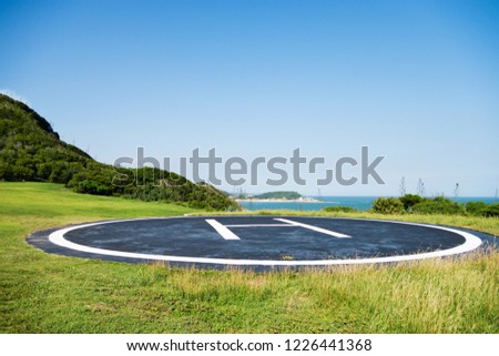 Empty helipad on island with blue sky background.