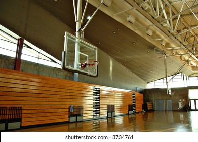 Empty High School Gym With Basketball Hoop And Bleachers