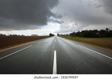 Empty highway (asphalt road) through the fields. Dramatic sky before the rain and thunderstorm. Concept landscape. Rural scene. Darkness, fall season, fickle weather, dangerous driving, road trip