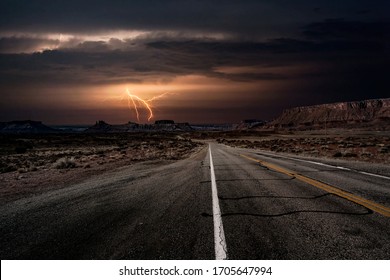 An Empty Highway Leading To A Lightning Storm In The Middle Of The Desolate Desert Near Moab, Utah, USA.