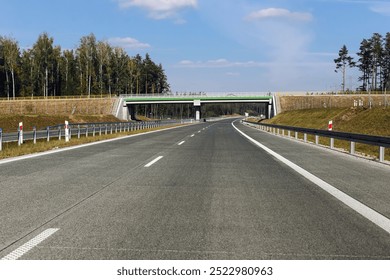 Empty highway view from a car perspective on a sunny day. Clear skies and smooth road ahead. Driving on the open highway during a daytime trip. Beautiful travel scene with daylight. Bridge over road.