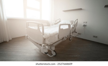 An empty hospital bed in a clean, modern room with soft sunlight coming through the window. The scene conveys a peaceful and sterile environment, ready for patient care and recovery. - Powered by Shutterstock