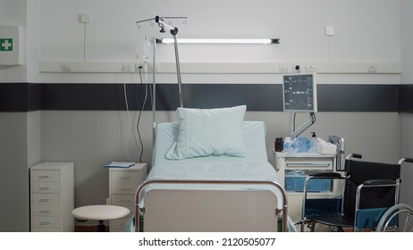 Empty Hospital Ward With Medical Equipment And Tools For Healthcare And Healing. Nobody In Emergency Room Bed At Facility With IV Drip Bag, Heart Rate Monitor And Instruments For Care