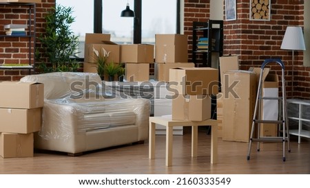 Empty household space with cardboard boxes used for relocation, moving home furniture in carton containers and storage equipment. No people in new apartment flat to movae into.