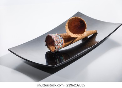 Empty Ice Cream Cones Resting On A Dark Tray Isolated On White Background