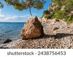 Empty idyllic stone beach on hiking trail along majestic cliffs between coastal villages Krvavica and Makarska, Dalmatia, Croatia, Europe. Majestic Makarska Riviera, Adriatic Mediterranean Sea. Summer