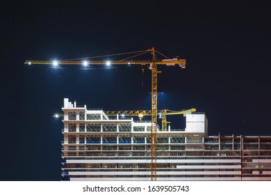 Empty Illuminated Construction Site And Yellow Crane At Night