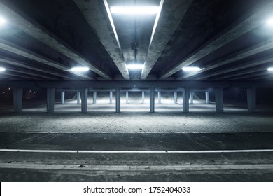 An empty illuminated motorway, bicycle road and pedestrian walkway under the bridge in a fog at night. Dark urban scene. Riga, Latvia. Dangerous driving, concept image - Powered by Shutterstock