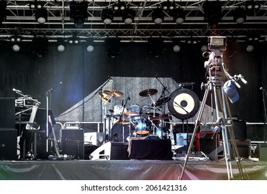 Empty Illuminated Stage With Drum Kit, Microphones And Film Camera