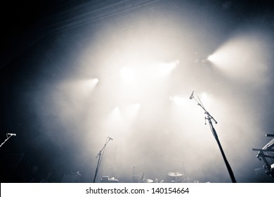 Empty illuminated stage with drumkit, guitar and microphones - Powered by Shutterstock