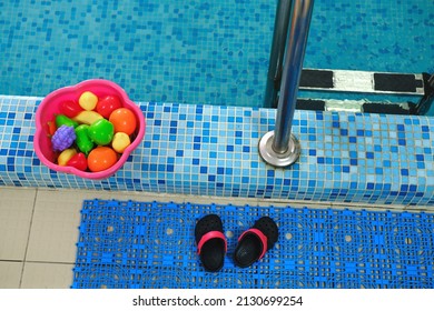 Empty Indoors Public Swimming Pool For Kids. Sports Balls. Children Center, Pool With Children Equipment. Flip Flops Near Side