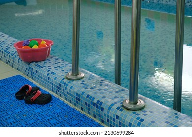 Empty Indoors Public Swimming Pool For Kids. Sports Balls. Children Center, Pool With Children Equipment. Flip Flops Near Side