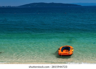 An empty inflatable dinghy washed ashore on a deserted beach, creating a dramatic and mysterious coastal scene. The abandoned boat evokes themes of survival, shipwreck, maritime accidents, rescue operations, and the power of the sea. A concept image suitable for travel, safety, environmental, and storytelling topics.