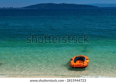 An empty inflatable dinghy washed ashore on a deserted beach, creating a dramatic and mysterious coastal scene. The abandoned boat evokes themes of survival, shipwreck, maritime accidents, rescue operations, and the power of the sea. A concept image suitable for travel, safety, environmental, and storytelling topics.