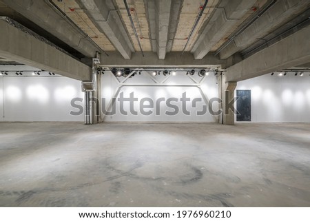empty interior of large concrete room as warehouse or hangar with spotlights