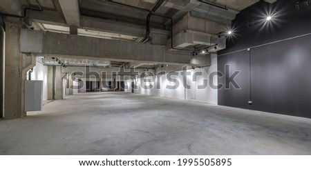 empty interior of large concrete room as warehouse or hangar with spotlights