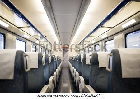 Empty interior of a passenger train car aka coach or carriage . Rows of unoccupied seats and folding tables in economy or second class.