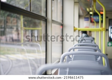 Empty interior of a tram, trolleybus or bus traveling through the city. Inside view. Selective focus. Small zone of sharpness. Daylight