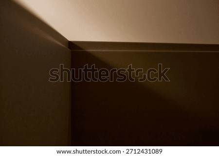 Empty interior wall corner showing geometric lines and sharp shadows with soft gradient lighting, abstract architectural background emphasizing minimalism and copy space