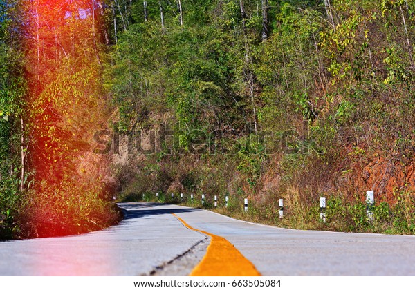 Empty interstate road with a sharp curve ahead\
- horizontal view with a light\
leak