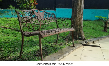 Empty Iron Bench In A City Park At Noon.