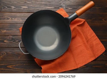 Empty Iron Wok With Napkin On Wooden Table, Top View