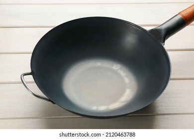 Empty iron wok on white wooden table. Chinese cookware