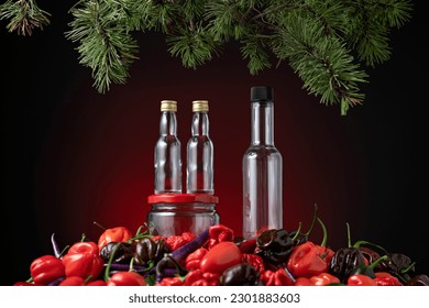 Empty jars for sauce and different types of peppers under branches of Christmas tree. Festive menu. Different varieties of hot peppers for sauce. Maroon background. Side view. Copy space. 