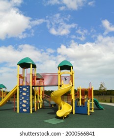 Empty Kids Outdoor Playground At Public Park With Blue Sky And Clouds In Background