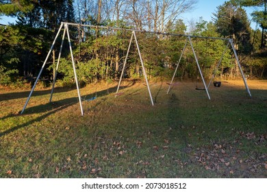 Empty kids swingset in a park playground at dusk, in autumn