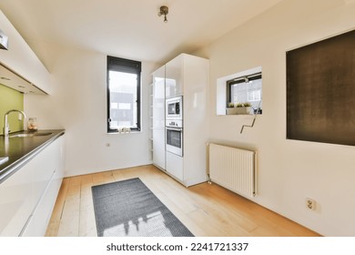 an empty kitchen and dining area in a house with white walls, hardwood flooring and black countertops on the wall