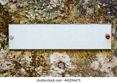 empty  label with rusty screws on old wall