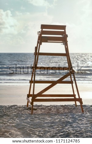 Empty lifeguard stand facing the ocean with small waves and blue skies