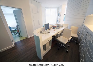 Empty Lit Reception Area In Dental Clinic. Working Place At Table With Computer.