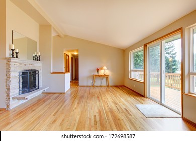 Empty Living Room With A Fireplace, Hardwood Floor And Sliding Glass Door Exit To The Deck