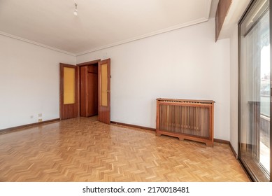 Empty Living Room With Herringbone Oak Parquet Floor, Wooden Radiator Cover, White Painted Walls And Brown Aluminum Joinery