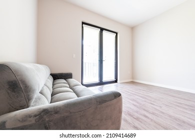 Empty Living Room Interior With Futon Couch Gray Sofa Furniture Closeup In New Modern Apartment House With Window Doors Balcony And Natural Light On Hardwood Laminate Floor